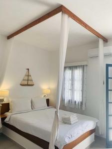 a white bedroom with a bed with a canopy at Endless Blue Studios in Myrtos