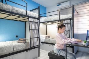a woman sitting at a desk in a room with bunk beds at Hostel Four Rooms in Ulcinj