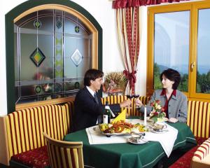 Ein Mann und eine Frau sitzen an einem Tisch in einem Restaurant in der Unterkunft Ferienhotel Hofer superior in Strass im Attergau