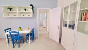 a kitchen with a white table and blue chairs at Lucy Apartment sul lungomare in Maiori