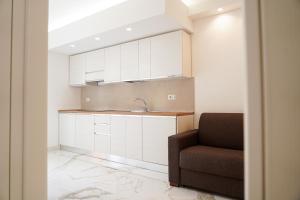 a kitchen with white cabinets and a sink and a chair at Kind House in Pozzallo