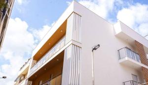 a white building with a street light in front of it at Kind House in Pozzallo