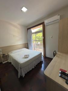 a bedroom with a bed and a large window at Hotel Santa Maria in Campo Mourão