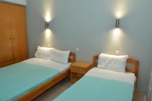two beds in a small room with lights on the wall at Hotel Filoxenia in Nei Poroi