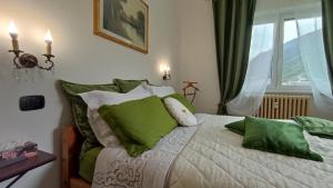 a bedroom with a bed with green pillows and a window at Tirano Express Comfort 2P Appartamento spazioso con vista montagne, ideale per famiglie e gruppi in Tirano