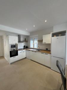 a kitchen with white cabinets and a white refrigerator at Eucaliptus in Camarles