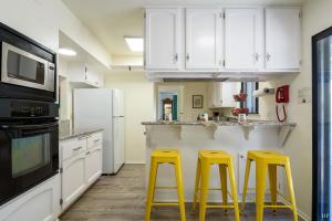 two yellow stools in a kitchen with white cabinets at Sea Change by Paradise Retreats in Santa Barbara