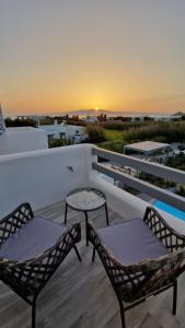 two chairs and a table on a balcony with the sunset at Apartment Filotimo with sea and sunset view in Kastraki