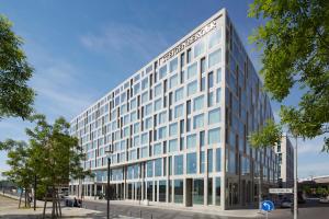 ein hohes weißes Gebäude mit Glasfenstern auf einer Straße in der Unterkunft Steigenberger Hotel Am Kanzleramt in Berlin