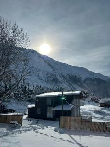 a house in the snow in front of a mountain at Oishe View in Stepantsminda