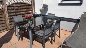 a glass table with chairs and flowers on a patio at Urlaubsapartment am Silbersee in Villach