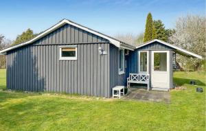 a blue shed with a white door on a yard at 2 Bedroom Lovely Home In Dannemare in Dannemare +2 photos