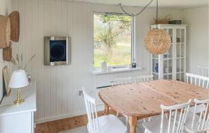 a dining room with a wooden table and white chairs at 2 Bedroom Lovely Home In Dannemare in Dannemare