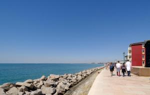 a group of people walking on a sidewalk next to the ocean at 1 Bedroom Lovely Apartment In Grado in Grado