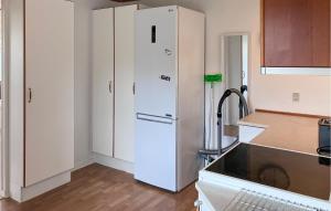 a kitchen with white cabinets and a refrigerator at Lovely Home In Kirke Hyllinge in Kirke-Hyllinge