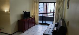 a living room with a couch and a tv and a window at Porto de Iracema Vista Mar in Fortaleza