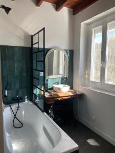 Charmante maison de campagne proche du lac de Paladru في Valencogne: حمام مزود بحوض استحمام ومغسلة ومرآة