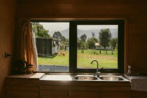 fregadero de cocina con ventana con vistas a un campo en Indómito Refugio, en Puelo
