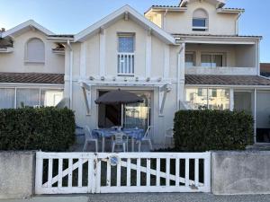 a house with a white fence and a table with an umbrella at Cadre idéal près de l'océan pour 4 personnes à Biscarrosse Plage - FR-1-831-6 in Biscarrosse