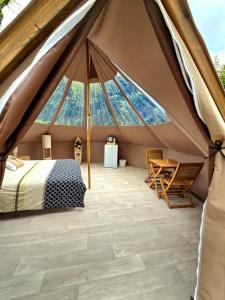 a bedroom in a tent with a bed and a table at Les nuits de Cassiopee in Sorde-lʼAbbaye