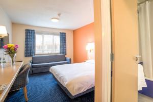 ハダーズフィールドにあるMetro Inns Huddersfieldのベッドとデスクが備わるホテルルームです。