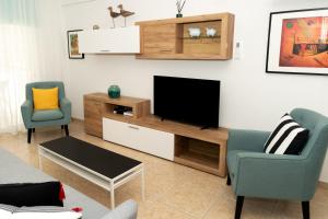 a living room with two chairs and a flat screen tv at Olivia Mackenzie 2 Bedroom Flat with Pool in Larnaka