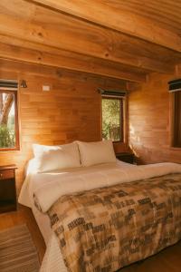 1 dormitorio con 1 cama grande en una cabaña de madera en Indómito Refugio, en Puelo