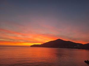 um pôr-do-sol sobre a água com uma montanha ao fundo em APARTMANI VUKADINOVIC LUX em Budva