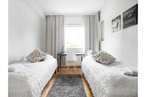two beds in a room with a desk and a window at Kotikaksio Grigio in Lahti