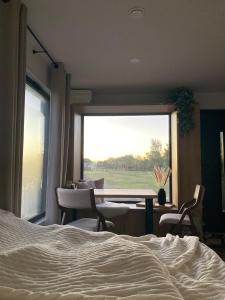 a bedroom with a large window with a table and chairs at Tiny House Boddenblick - Ostsee in Groß Kordshagen