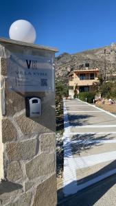 a sign on a stone wall with a walkway at Villa Kyma by the sea, in South Crete in Keratokampos