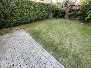 a grassy yard with a tree and a brick sidewalk at Holiday House La Fornace in Pontedera