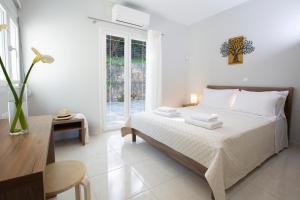 a white bedroom with a bed and a table at Theros Apartment 1 in Yénion +52 photos