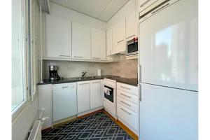 a kitchen with white cabinets and a black and white rug at Kotiyksiö Vaughan in Lahti