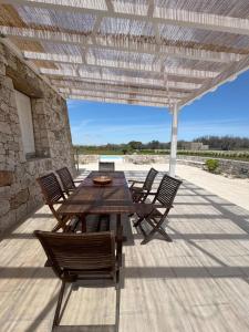 Una mesa y sillas de madera en un patio. en Villa Virò by salentoltremare, en Alessano