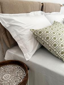 Una cama con almohadas blancas y una cesta. en Villa Virò by salentoltremare, en Alessano