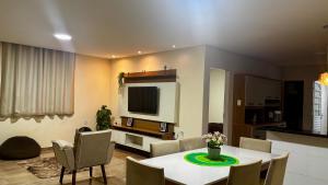 a living room with a table and chairs and a tv at 4 quartos, sendo 2 suítes - uma com varanda privativa, a 700m da Praia da Boca da Barra e 2,5km da orla de Tamandaré, Wifi 200MB e cozinha completa - Piscina e estacionamento privativos - Ideal para grupos e famílias - tranquilo para home office in Tamandaré