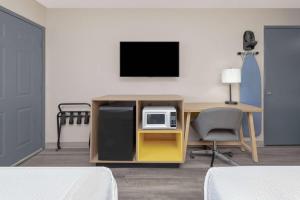 a room with a desk with a microwave and a tv at Days Inn by Wyndham Wichita Falls in Wichita Falls