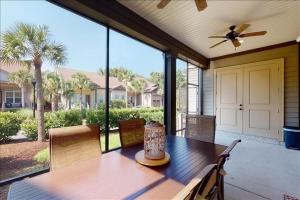 a wooden table on a porch with a ceiling fan at Garden Cottage 10 in Jekyll Island