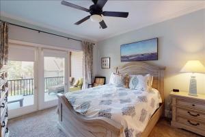 a bedroom with a bed with a ceiling fan and a balcony at Garden Cottage 10 in Jekyll Island +38 photos