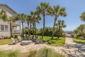 a patio with chairs and palm trees in front of a house at Garden Cottage 09 in Jekyll Island