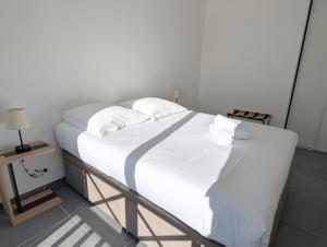 a white bed with white sheets and pillows on it at Appartement lumineux avec balcon & aperçu mer in Pornic