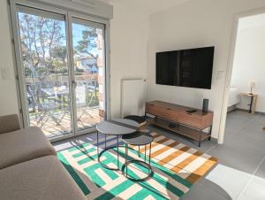a living room with a couch and a tv at Appartement lumineux avec balcon & aperçu mer in Pornic