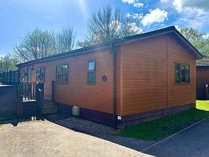 a small wooden cabin with a door in a yard at Family Friendly Lodge sleeping 5 with Hot Tub - Devon in Chudleigh