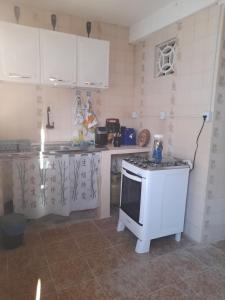 a kitchen with a white stove top oven next to a counter at Pousada Marília Rodrigues in Piranhas