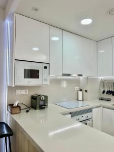 a kitchen with white cabinets and a microwave at Condo with solarium in Laguna Beach Resort In Los Balcones in Torrevieja in Torrevieja +20 photos