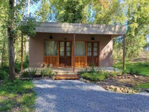 a small house with a porch in the woods at Cuenca del Bosque in Tandil
