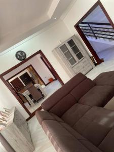 un salon avec un canapé et une horloge au mur dans l'établissement De-Image Villa, à Apenkwa