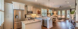 a large kitchen with white appliances and a living room at Poolside Cottage 32 in Jekyll Island