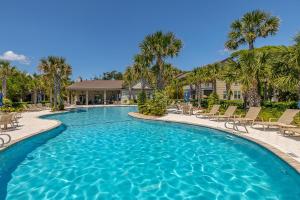 a swimming pool with chairs and palm trees at Poolside Cottage 32 in Jekyll Island